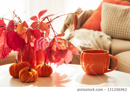 Cozy Autumn Living Room Scene with Mug, Notebook and Seasonal Decor under Sun Light 131206962