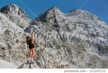 Woman Hiker with Backpack and Poles Standing on Rock 131207232