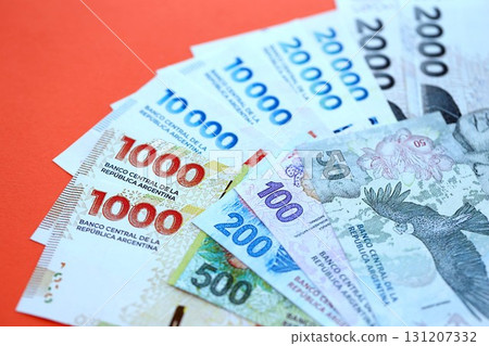 Argentine pesos money bills in big amount lies on red color table close up. Finance and banking concept 131207332