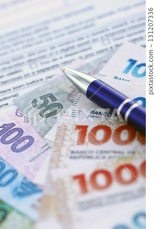Argentine pesos money bills in big amount lies on table with pen and tax forms close up. Finance and banking concept 131207336