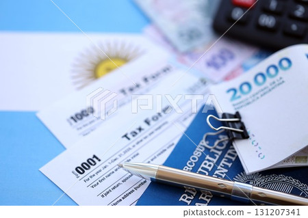 Argentine pesos money bills in big amount lies on table with pen, calculator, passport and tax forms close up. Finance and banking concept 131207341