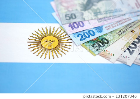 Argentine pesos money bills in big amount lies on Argentina flag close up. Finance and banking concept 131207346