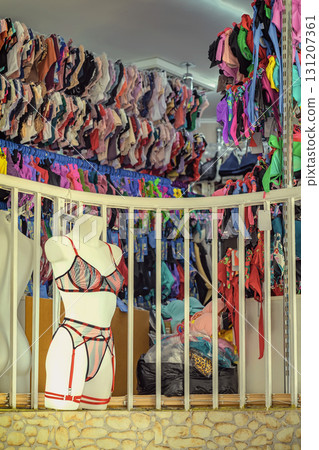 Lingerie mannequin displayed in front of crowded wall of colorful bras and panties inside fashion retail store. Concept of body positivity, female fashion, intimate diversity 131207361