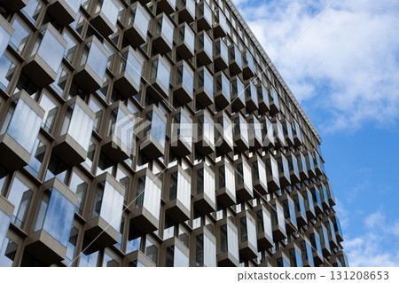 Modern building facade featuring geometric arrangement of protruding windows. The design emphasizes clean lines, symmetry, and minimalist approach to urban architecture Modern building facade featuring geometric arrangement of protruding windows. The design emphasizes clean lines, symmetry, and minimalist approach to urban architecture 131208653