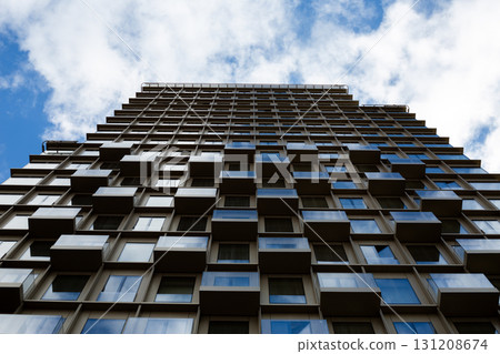 Modern urban architecture shot from below, focusing on geometric pattern of building facade. Symmetrical design and clean lines emphasize minimalist aesthetics in contemporary construction 131208674