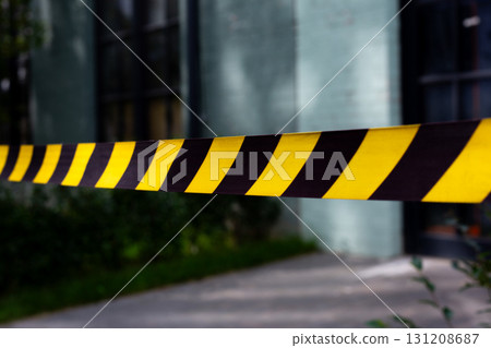 Close up of caution tape marking crime scene. The yellow and black stripes emphasize the restricted area, creating clear boundary around the scene, ideal for news stories about crime investigation 131208687