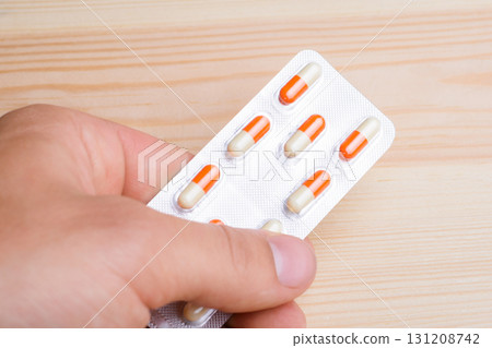 Hand holding pills over wooden background Hand holding pills over wooden background 131208742