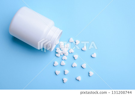Scattered from the bottle white love pills on blue background. Concept of love pills 131208744