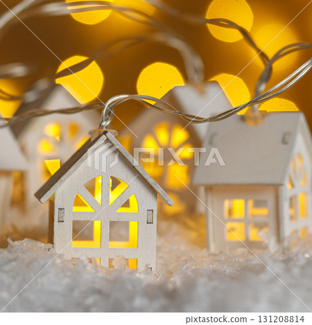 Christmas wooden houses garlands with lights in the snow on glowing lights bokeh background 131208814