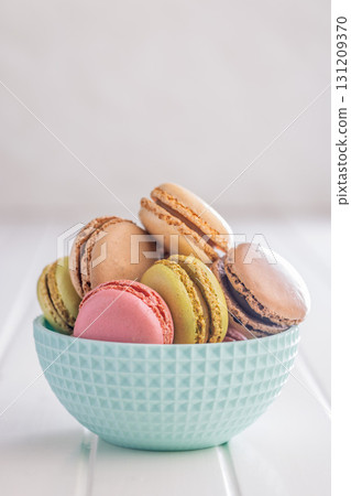 Different flavors of macarons. Colourful macaroons in bowl on white table. 131209370
