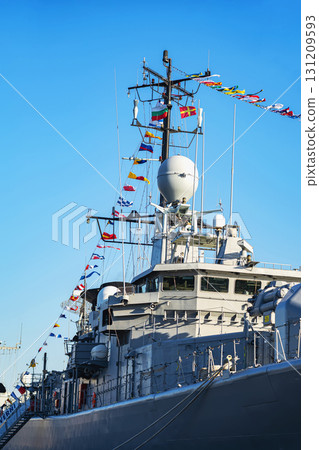 Close-up of naval warship mast decorated with colorful maritime signal flags on clear sky. Concept of navy tradition, marine communication, military ship ceremony Close-up of naval warship mast decorated with colorful maritime signal flags on clear sky. Concept of navy tradition, marine communication, military ship ceremony 131209593
