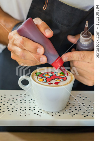 Barista creating vivid latte art with heart using colored syrups on coffee foam in white cup. Concept of latte art, barista skill and coffee design creativity 131209594