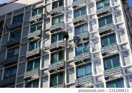 A man is currently in the process of climbing up the side of a building 131209611