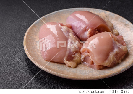 Raw chicken thigh fillet without skin and bone with salt and spices. Raw chicken fillet for cooking Raw chicken thigh fillet without skin and bone with salt and spices. Raw chicken fillet for cooking 131210552