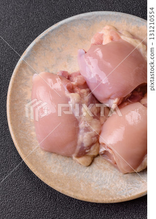 Raw chicken thigh fillet without skin and bone with salt and spices. Raw chicken fillet for cooking Raw chicken thigh fillet without skin and bone with salt and spices. Raw chicken fillet for cooking 131210554
