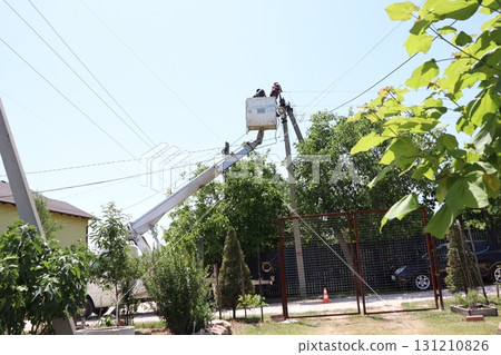 Dedicated workers are diligently repairing power lines in a busy residential area today 131210826