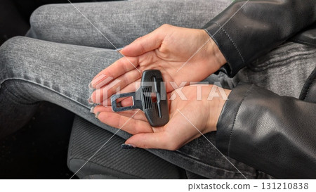 A pair of hands grasping a car seatbelt clip, showcasing its essential role in vehicle safety 131210838