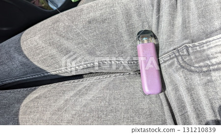A Casual Vaping Moment A Trendy Vape Pen Resting Stylishly Upon a Pair of Jeans During Leisure Time A Casual Vaping Moment A Trendy Vape Pen Resting Stylishly Upon a Pair of Jeans During Leisure Time 131210839