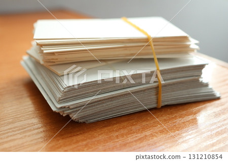 A Neatly Arranged Stack of Blank Cards Securely Tied with a Rubber Band on a Wooden Table 131210854