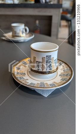 An Elegant Coffee Cup beautifully placed on a Table alongside a Decorative Saucer An Elegant Coffee Cup beautifully placed on a Table alongside a Decorative Saucer 131210966