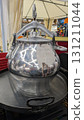 A shiny silver kettle gleams brightly at the bustling outdoor market, attracting attention 131211044