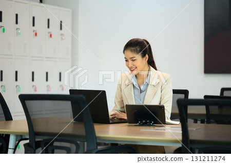 Confident businesswoman in blazer using laptop at desk 131211274