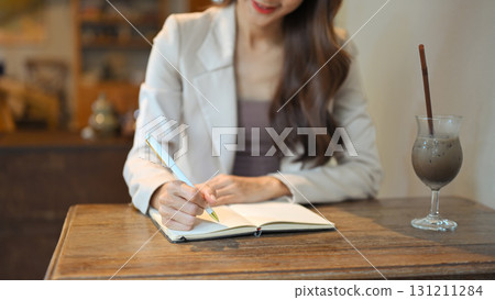 Businesswoman planning tasks in a notebook at a cozy coffee shop 131211284