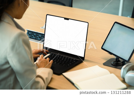 Businesswoman working on laptop with blank white screen in modern office Businesswoman working on laptop with blank white screen in modern office 131211288