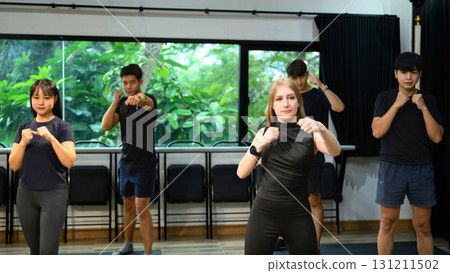 Multicultural group engaged in a boxing workout routine in a bright studio 131211502