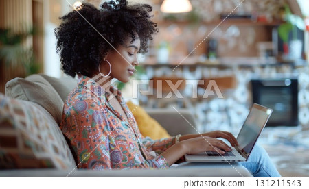 Woman seated on couch using laptop for work or leisure 131211543