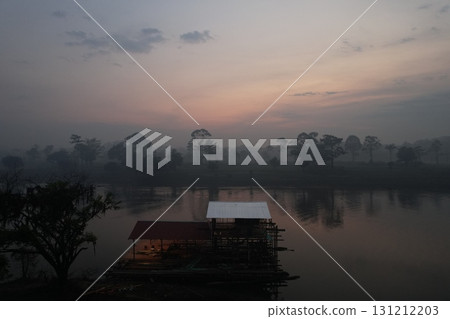 Early morning mist rising over the river with a wooden structure nearby 131212203