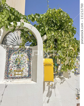 Bright yellow mail box adorned with greenery on a beautiful wall in Tunisia inviting the locals to 131212780