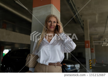 Woman in white blouse talking on phone in a modern parking garage during the daytime 131212887