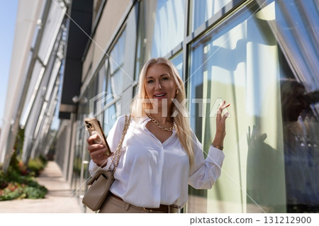 Woman enjoying a sunny day while taking a stroll near modern architecture and glass window Woman enjoying a sunny day while taking a stroll near modern architecture and glass window 131212900