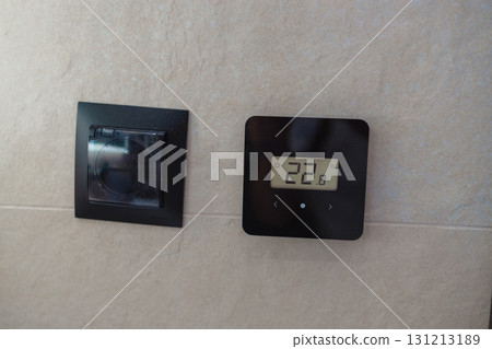Digital thermostat on wall showing room temperature 131213189