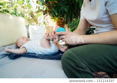 Father massages baby's legs with massage ball. Healthy massage. Massage therapist. Sensory tactile activities. Children health. Massage textured balls for kids. Earlier development. Focus picked. 131214107