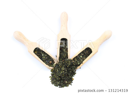 Green tea with herbs in wooden spoons on a White Background. 131214319