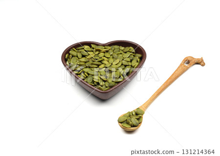 Pumpkin seeds in a wooden bowl on a white background Pumpkin seeds in a wooden bowl on a white background 131214364