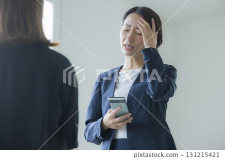 A woman in a suit manipulating a smartphone 131215421