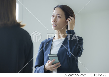 A woman in a suit manipulating a smartphone 131215422