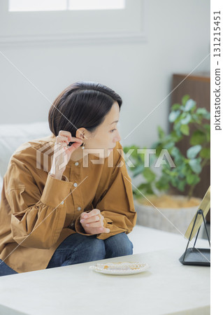 A woman looking in the mirror in the living room A woman looking in the mirror in the living room 131215451