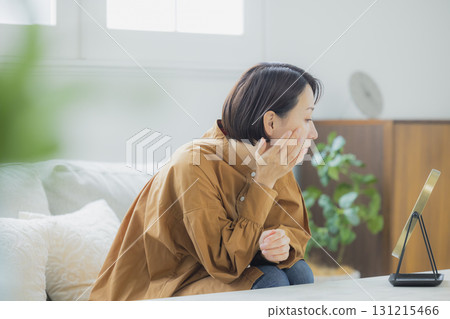 A woman looking in the mirror in the living room 131215466