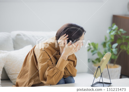 A woman looking in the mirror in the living room A woman looking in the mirror in the living room 131215473
