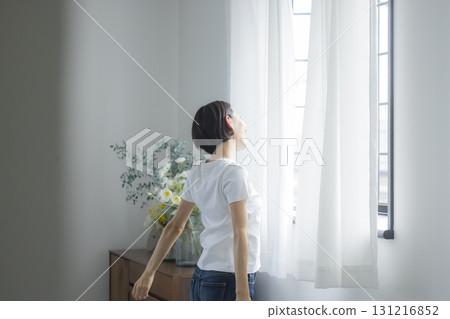 Woman opening curtain Woman opening curtain 131216852