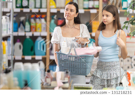 Mom with daughter filled basket with purchases in household store, looking for something new products Mom with daughter filled basket with purchases in household store, looking for something new products 131218231