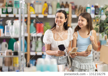 Woman with daughter choosing hairbrush in store 131218276
