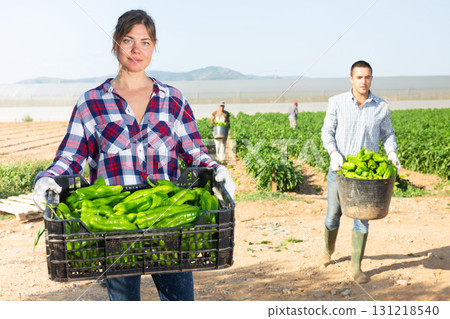Woman farmer with crate of green pepper 131218540