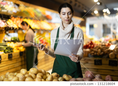 Upset woman owner of greengrocer with paper document and phone 131218604