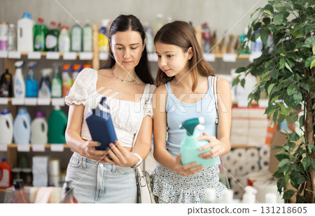 Woman with preteen girl choosing cleaning spray in household store Woman with preteen girl choosing cleaning spray in household store 131218605
