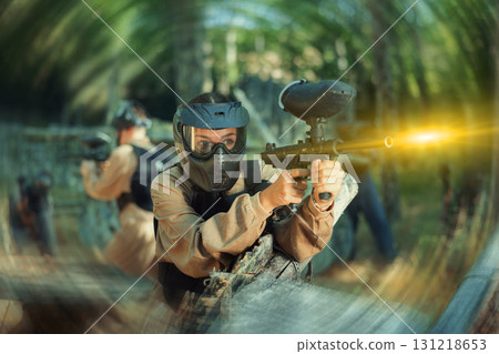 Young woman paintball player shooting with paintball marker 131218653
